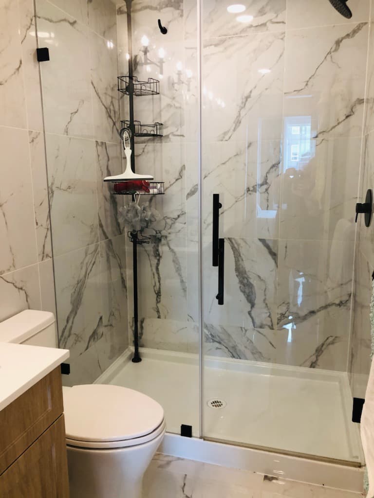 Marble shower stall after deep clean — grout scrubbed and glass sparkling